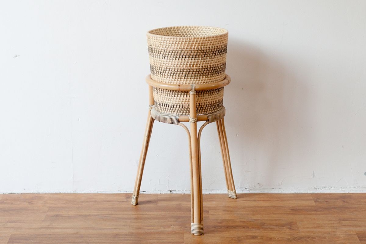 A wicker basket placed on a wooden stand, featured in a guide to repairing wicker furniture. 