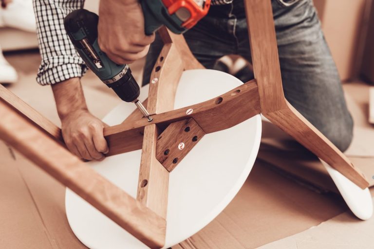 A man drills into a chair as part of a vinyl furniture repair project.